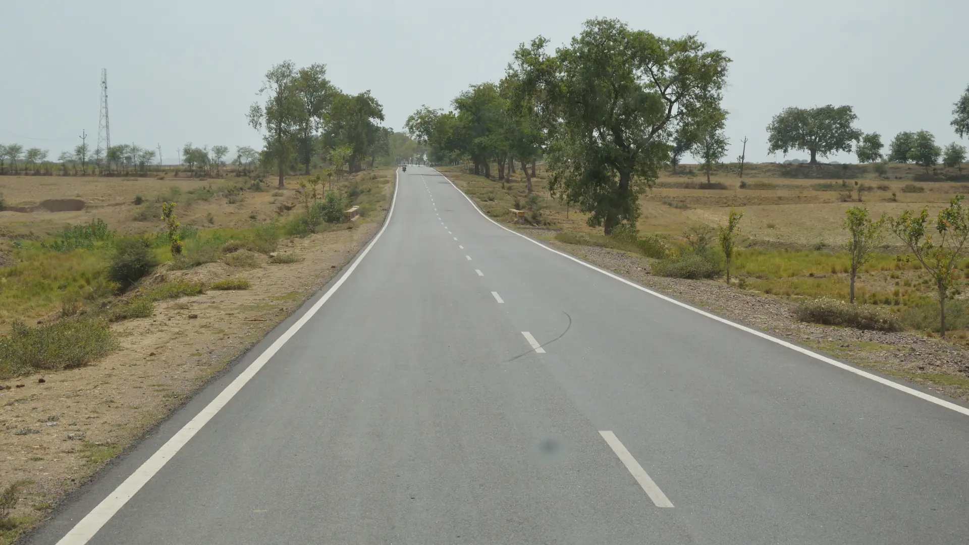An open two-lane highway in Uttar Pradesh under a wide sky